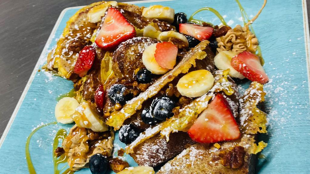 Banana Bread French Toast · Three pieces of our banana bread dipped in our homemade french toast butter, topped with fresh bananas, blueberries, pecans, and caramel sauce.