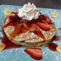 Strawberry Banana Pancakes · Four pancakes filled with fresh slices of banana and topped with fresh bananas, strawberry c...