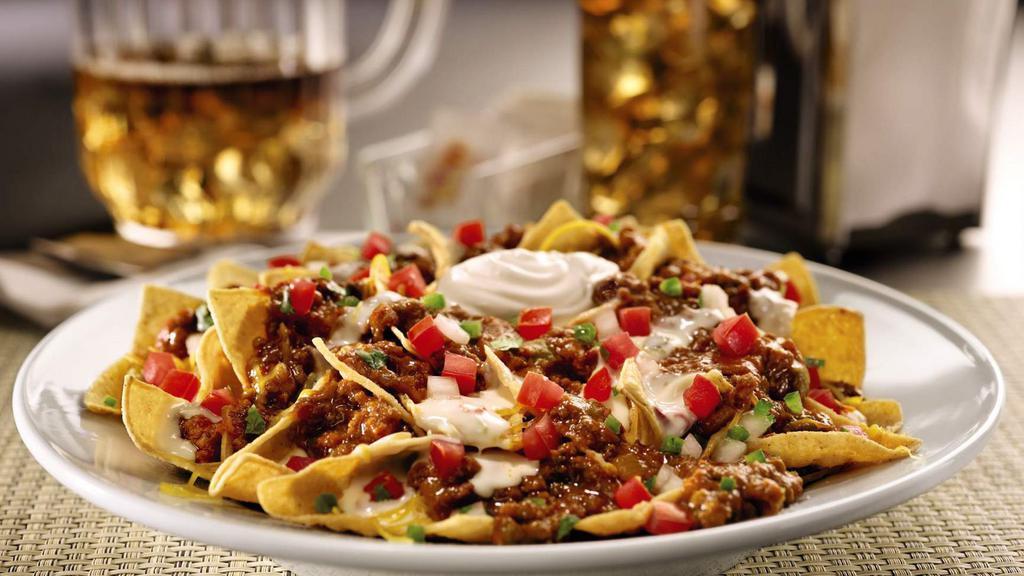 Zesty Nachos. · Tortilla chips cooked fresh to order. Served with Pepper Jack queso, shredded Cheddar cheese, seasoned nacho meat, freshly made pico de gallo and sour cream on the side to keep chips crispy until you’re ready to assemble & devour!