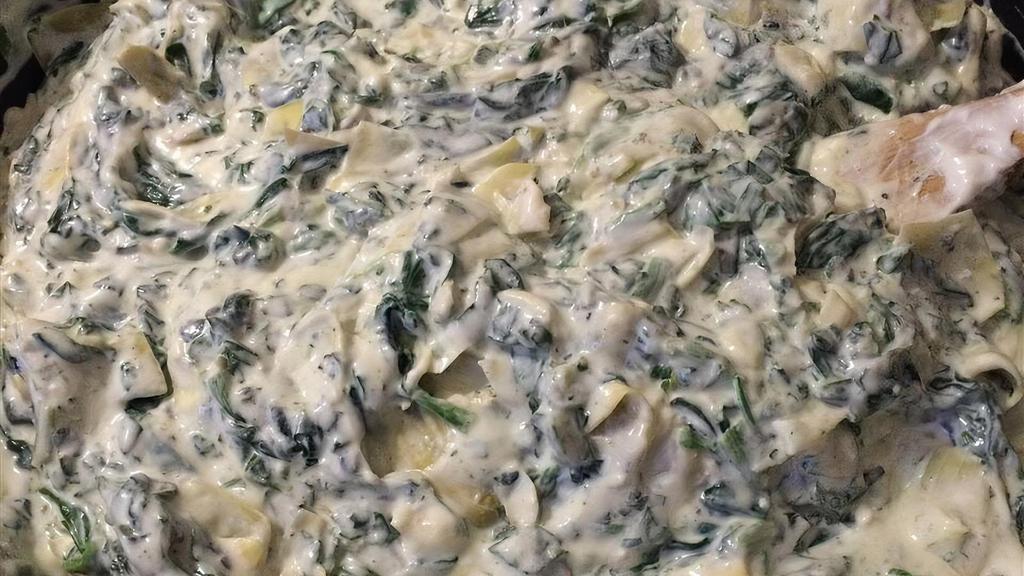 Spinach Artichoke Dip · Fresh spinach in a creamy artichoke dip served with fresh cut tortilla chips and toasted pita bread.
