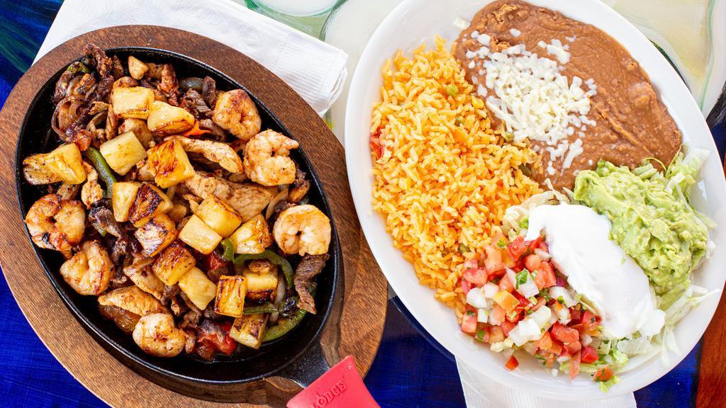 Fajitas Texanas · Shrimp, chicken and steak grilled with tomatoes, onions, bell peppers, and pineapple. Served with rice, beans, lettuce, guacamole, tomatoes, sour cream, and tortillas.