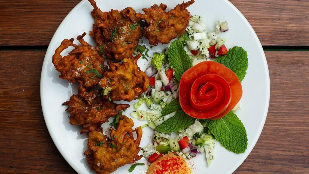 Onion Pakora · A tea-time favorite, sliced onions with diced potatoes and spinach complimented with spices and battered with chickpea flour and fried until golden brown.