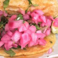 Al Pastor Taco · Pork marinated in adobo, avocado cilantro salsa, pineapple, onion, and cilantro.