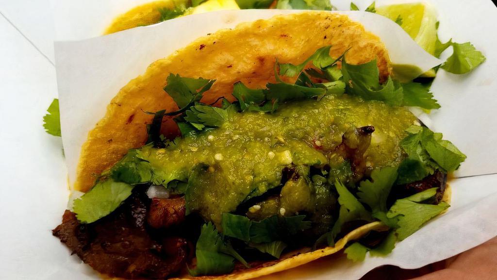 Bistec Taco · Sliced sirloin marinated in Wisconsin beer, pinto beans, tomatillo salsa, onion, and cilantro.
