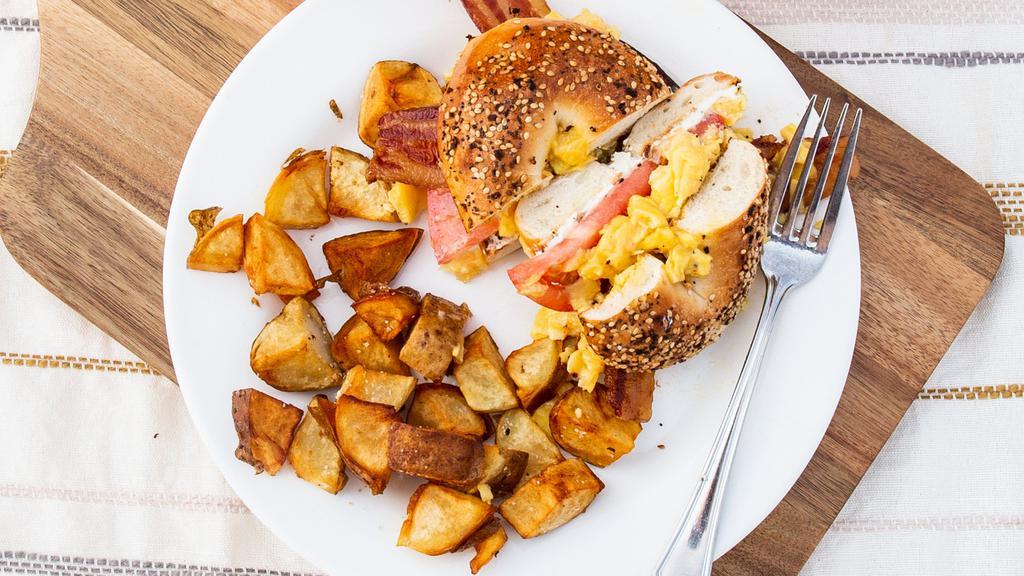 Everything Bagelwich · Grilled everything bagel, bacon, scrambled eggs, tomato, chive cream cheese. Served with home fries.