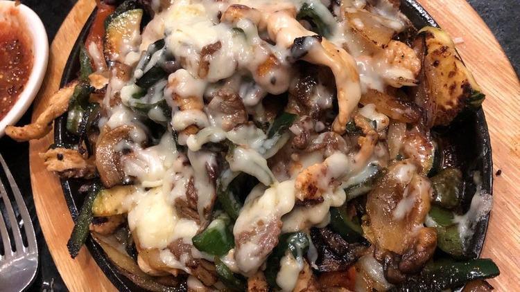 Flaming Cheese Fajitas · Grilled strips of chicken, steak, onions, zucchini, mushrooms, poblano peppers and tomatoes, served on a skillet covered with flaming melted cheese, garnished with fajita salad.