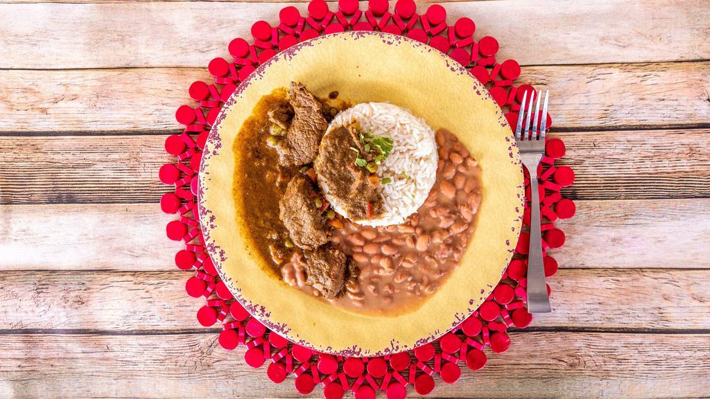 Frejoles Con Seco · Beef cooked in cilantro sauce served with side of bacon beans, white rice and onion salad.