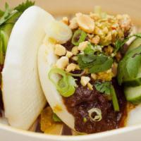 Szechuan Beef Bao · Wok fired marinated flank, pickled peppers, cilantro, crushed peanuts (2pcs).
