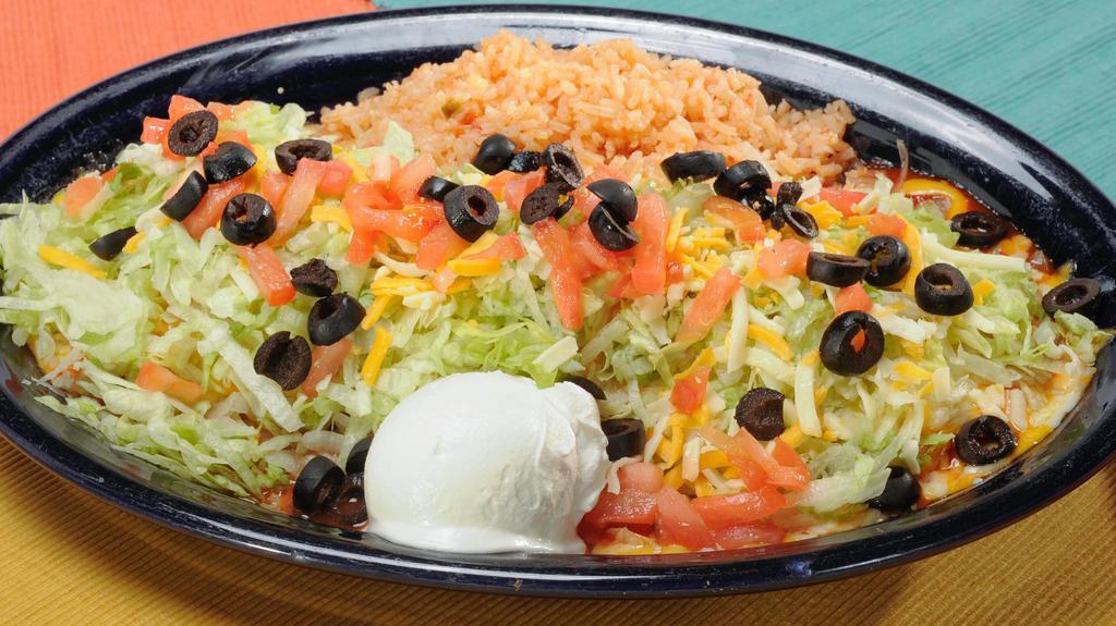 Burrito Fantastico · Soft flour tortilla filled with shredded beef or chicken, beans and cheese. Topped with ranchero sauce, lettuce, black olives, tomatoes and our cream. Served with rice.