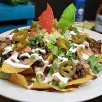 Nachos Mexicanos · Crisp tortilla chips topped with melted Chihuahua cheese, beans, jalapeño peppers, sour crea...
