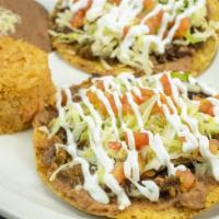 Dos Tostadas Con Arroz Y Frijoles · Two tostadas with Mexican rice and refried beans.
