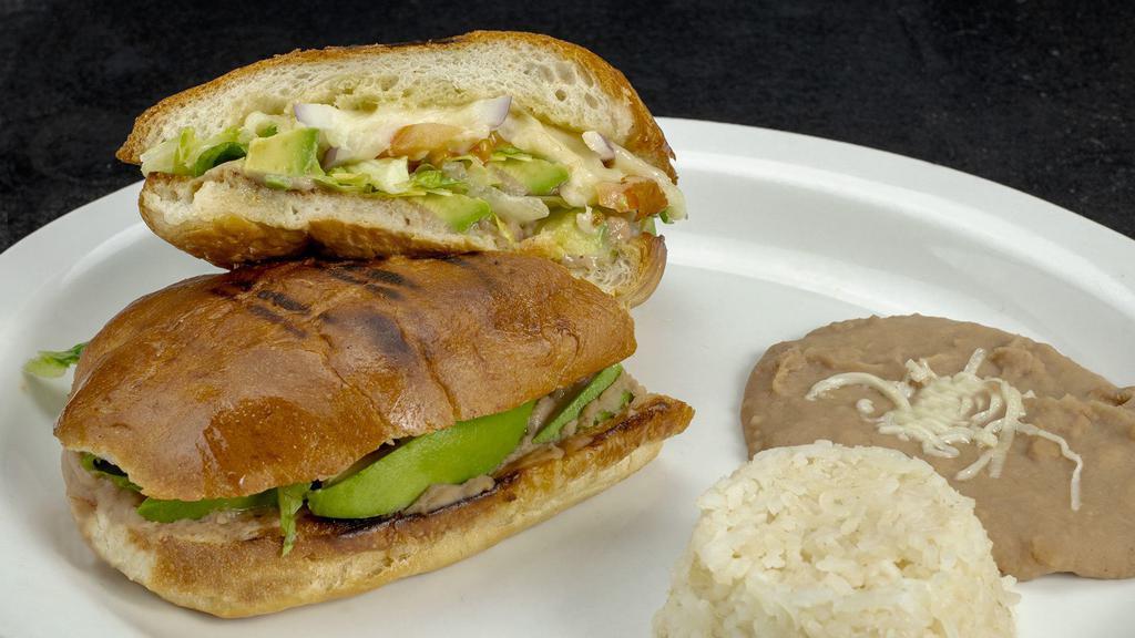 Avocado Torta · Mexican sandwich filled with fresh avocado slices, refried beans, cheese, lettuce, tomato slices, and mayonnaise. Served with refried beans and white rice.
