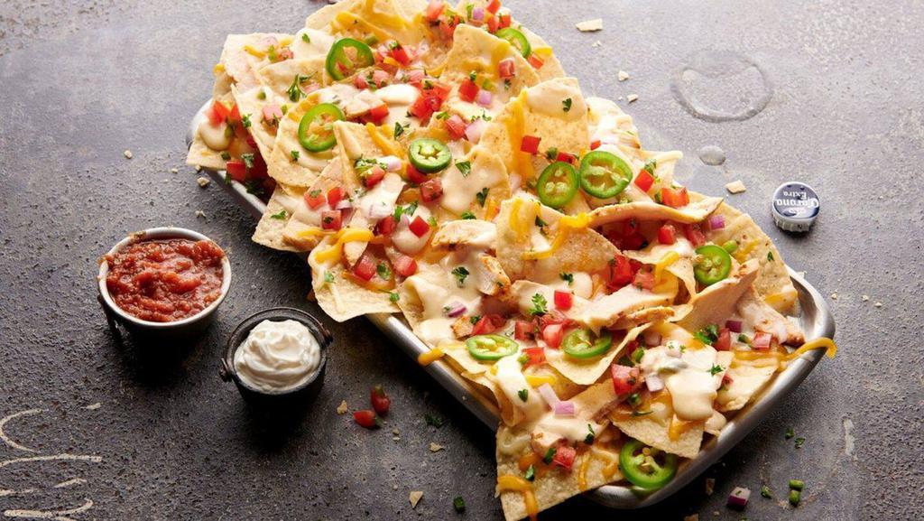 Legendary Loaded Nachos · Grilled chicken layered with shredded cheddar cheese, white queso, jalapeños and pico de gallo. Served with a side of sour cream and salsa