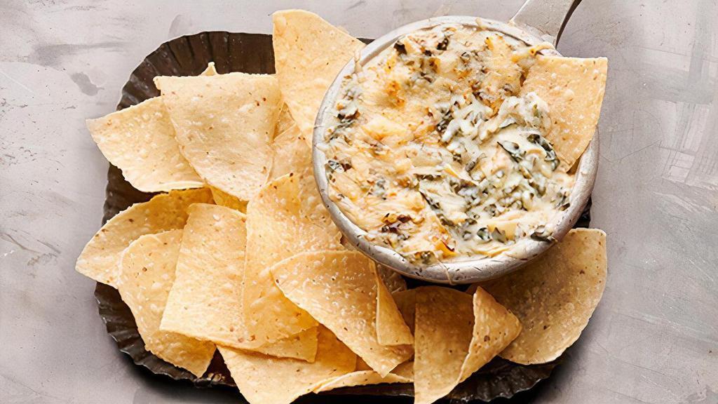 Spinach-Artichoke Dip · Creamy white American and Asiago cheeses, spinach and roasted artichokes, topped with shredded parmesan cheese. Served with tortilla chips, garlic-buttered crostini and salsa