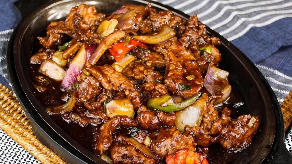 092 Sizzling Beef · Tender sliced beef, bell peppers, and onions in black bean sauce on a sizzling platter.
