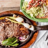 Carne Asada A La Mexicana · Tender rib-eye steak grilled with onions. Served with rice, beans, guacamole salad and choic...