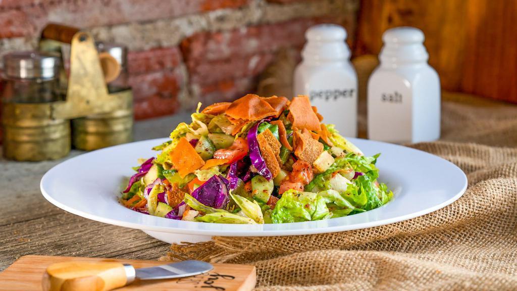 Fattoush Salad · A delicious combination of crisp romaine lettuce, tomato, cucumber, onion, shredded carrots and red cabbage, topped with fried Pita chips. Served with our famous homemade Fattoush dressing