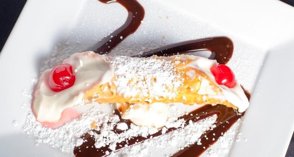Cannoli · A delicate, crispy pastry filled with sweetened orange whipped ricotta and sprinkled with powdered sugar.