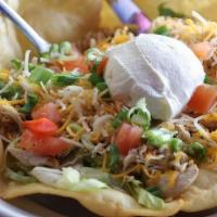 Taco Salad · A large tortilla bowl filled with shredded lettuce, cheese, tomato, chives, and sour cream