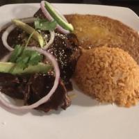 Mole Con Pollo · A staple dish in Mexican cuisine. Made with over 10 different spices including cacao, cinnam...