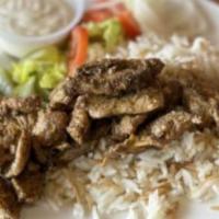 Chicken Shawarma Platter · Seasoned chicken atop rice pilaf. Served with a side of tahini dressing, Mediterranean pickl...