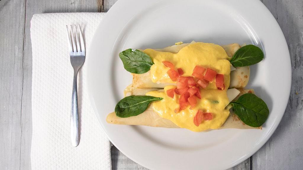 Farmer Stuffed Crêpes · Two crêpes stuffed with Swiss cheese, scrambled eggs, fresh spinach, mushrooms and onions then topped with a rich hollandaise sauce and diced tomatoes.