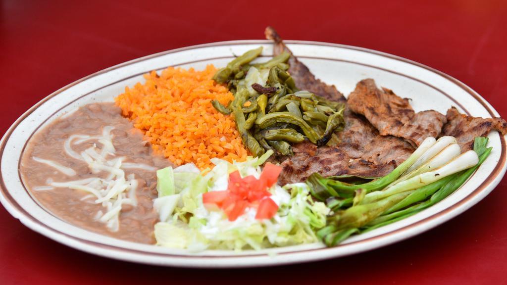 Bistec Asado (Grilled Steak) · Thinly sliced pieces of steak, seasoned and grilled. Topped with grilled green onions and pieces of grilled cactus. Comes with rice & beans topped with cheese.