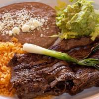 Carne Asada · Tender roast beef with beans rice guacamole salad and 3 tortillas.