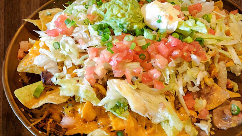Nachos Supreme · Crisp tortilla chips loaded with chicken, ground beef, shredded beef, beans and cheese dip sauce. Topped with lettuce, tomatoes, guacamole and sour cream.