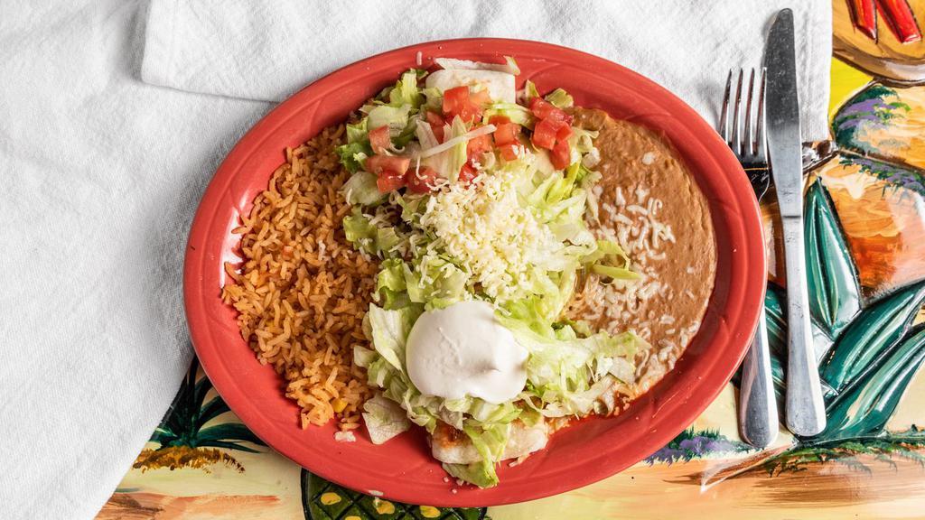 Burrito Supremo · 1 burrito filled with your choice ground beef or shredded chicken, topped with red sauce, lettuce, sour cream and tomatoes. Served with rice and beans on the side.