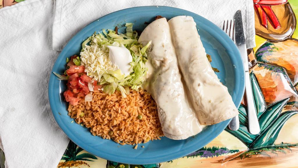 Burritos Fajitas · 2 burritos filled with choice of grilled steak or chicken, bell peppers, and tomatoes. Covered with nacho cheese and served with crema salad and choice of rice or beans.
