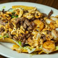 Nachos Al Carbon · Tender grilled chicken, steak and shrimp atop a bed of tortilla chips covered with shredded ...