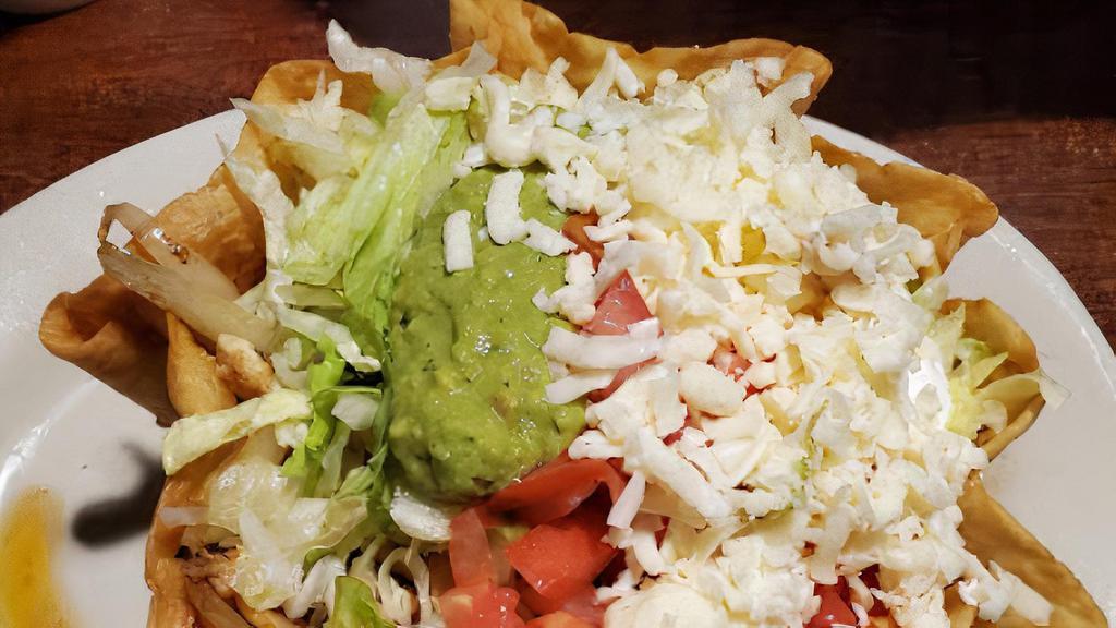 Taco Salad · Our classic salad of lettuce in a flour tortilla shell with tomatoes, cheese, sour cream, guacamole and beans lining the shell. Topped with your choice of ground beef, chicken or beef tips.