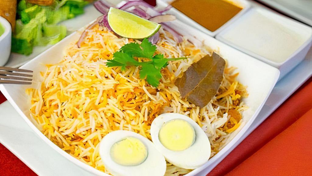 Vegetable Dum Biryani · Hyderabad dum-style layered, saffron-flavored basmati rice cooked with vegetables marinated in Nizami spices. Served with salan and raita. Gluten free.