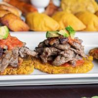 Tostones Con Carne Asada · 3 fried green plantains topped with steak, thin slices of avocado, sautéed onions, and tomat...