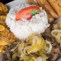 Bistec Encebollado · Steak sautéed with onions and served with rice, cassava, and green plantains.