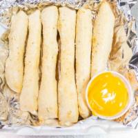 Breadstix · Six breadstix and a cup of cheese sauce.