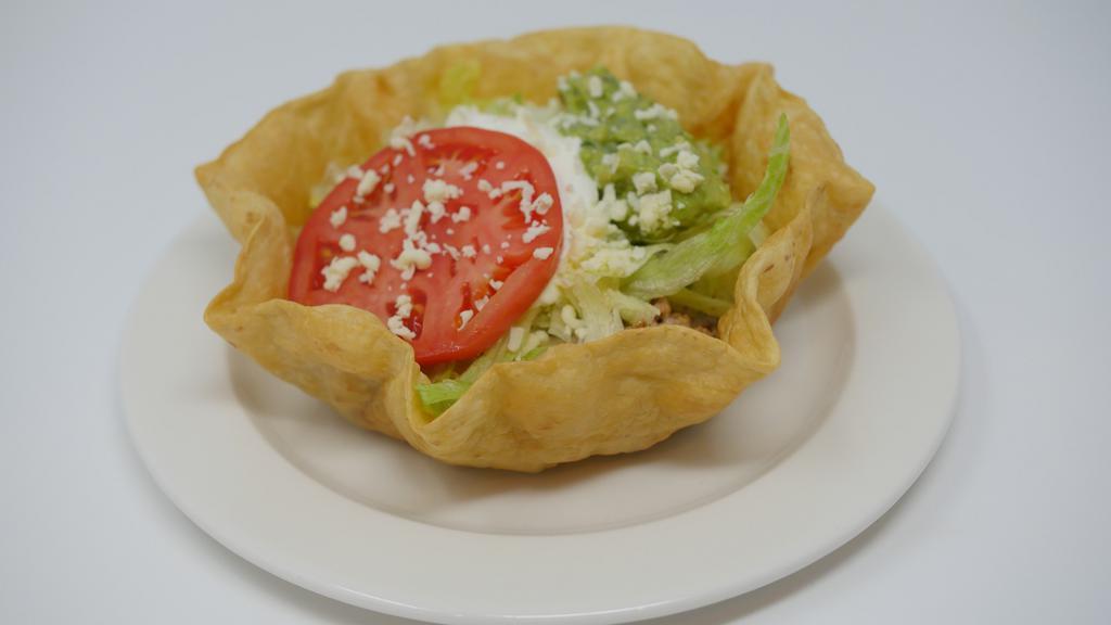 Taco Salad · A crispy flour tortilla with melted cheese sauce topped with seasoned ground beef or shredded chicken and tomato, cheese, guacamole, and sour cream.
