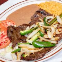 Carne Asada Al Carbon · Skirt steak cooked on the grill with onions and jalapeno peppers. Served with refried beans,...