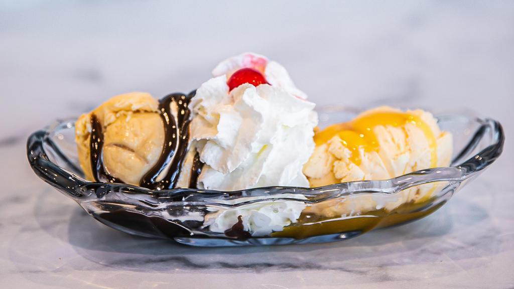 Twin Treat · Two sundaes in one dish!  Two scoops of vanilla ice cream with hot fudge on one and butterscotch on the other, whipped cream and a cherry