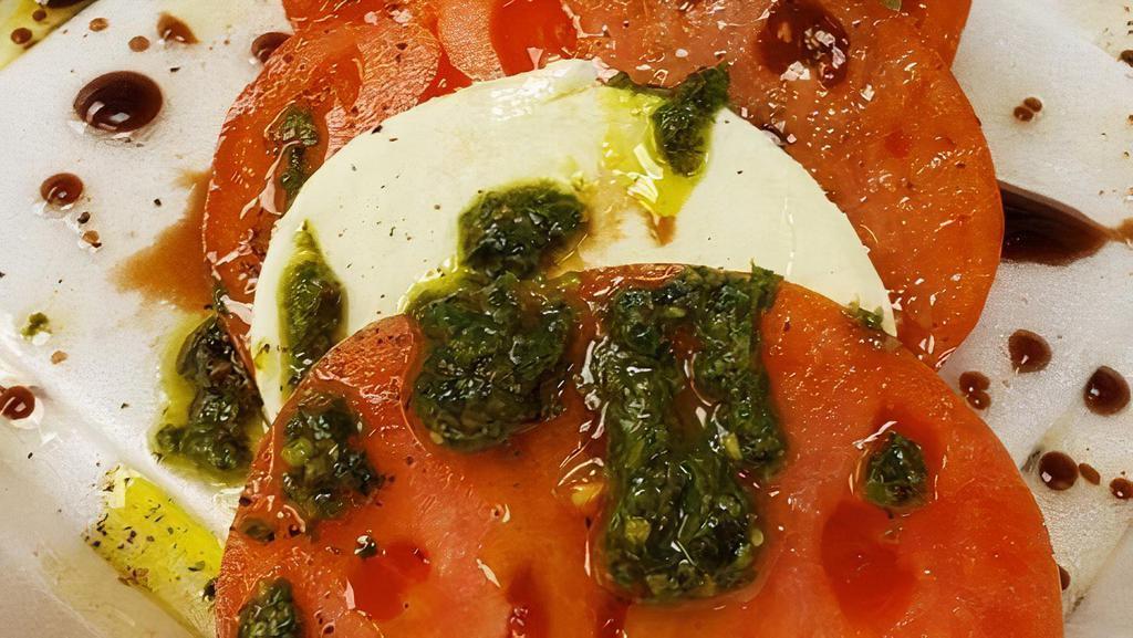 Mozzarella Caprese · Fresh Mozzarella layered with ripe tomato and fresh basil pesto, sprinkled with a bit of Italian sea salt and cracked black pepper, then drizzled with our house-made balsamic dressing.