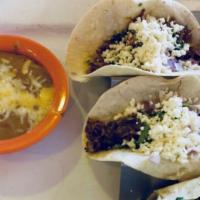 Tacos De Bistek · Thin pieces of steak grilled and served on a flour tortilla. Topped with fresh onions, cilan...