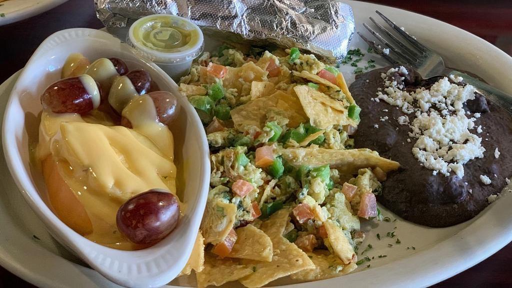 Migas · Two eggs scrambled with corn tortilla chips, tomatoes, jalapeno and cilantro. Served with refried black beans and fresh fruit drizzled in our homemade mango sauce. Served with flour tortillas.