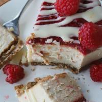Raspberry White Chocolate Cheesecake (Gf) · graham cracker crust, white chocolate cheesecake, raspberry topping, fresh raspberries