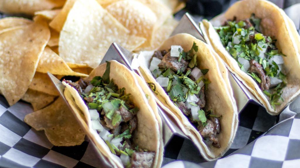 Side Street Taco · Corn tortillas, skirt steak, diced onions, cilantro, fresh lime, and side of spicy crema. Served with chips and salsa.