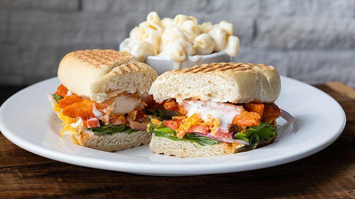 Buffalo Tenders Panini · Lightly breaded tenders tossed with buffalo wing sauce, Cheddar, ranch dressing, field greens, tomatoes, and red onions on a French roll. Served with your choice of side.
