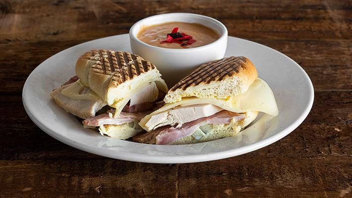 Cuban Panini · Roasted turkey and oven baked ham carved to order, pickle, Swiss, and honey dijon on a French roll. Served with your choice of side.