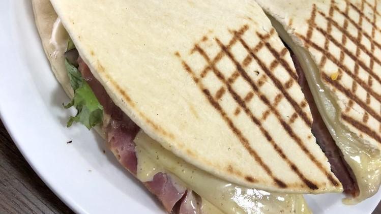 Ham Panini · Oven baked ham, honey dijon, light mayonnaise, Swiss, field greens, tomatoes, and red onions on flatbread. Served with your choice of side.