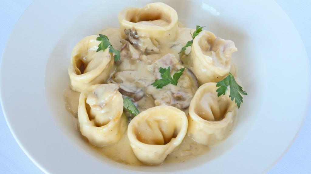 Tortelloni Alla Papalina · Home-made pasta filled with ricotta, sauteéd in olive oil, onions, pancetta, mushrooms, and cream.