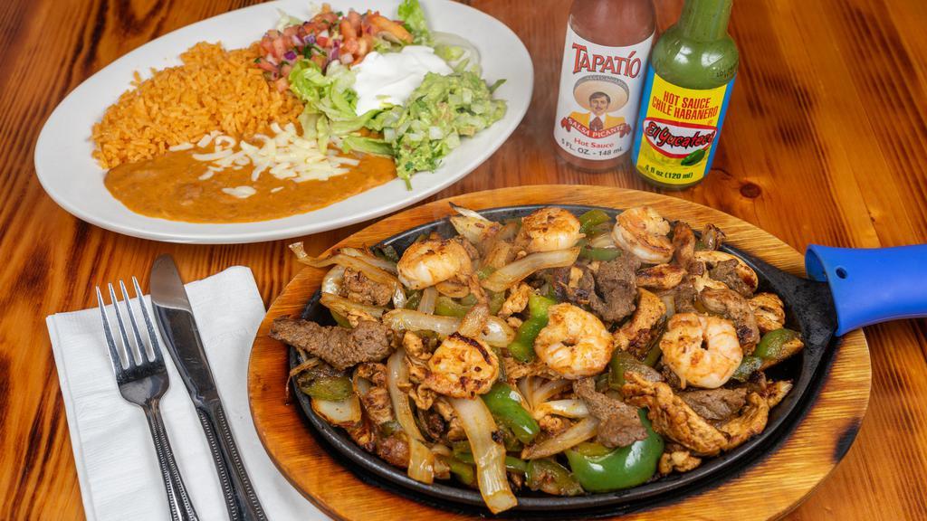 Texas Fajitas · Steak, chicken and shrimp with sautéed onion, bell peppers and tomatoes. Served with lettuce, guacamole, sour cream, pico de gallo, rice, refried beans and corn or flour tortillas.